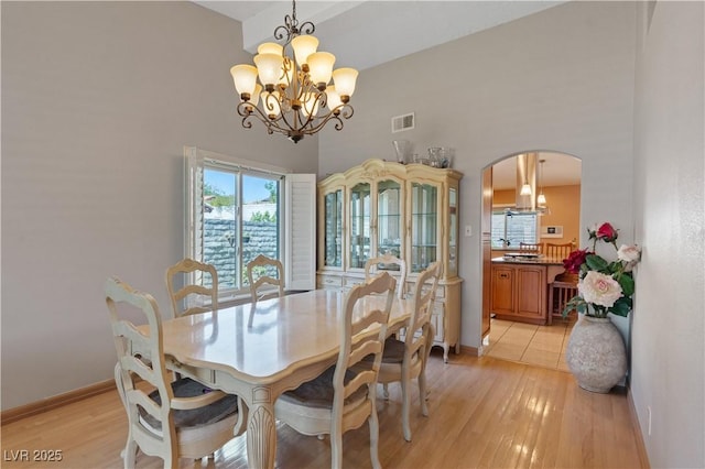 3361 Iberia St, Las Vegas, NV 89146 - dining space with arched walkways, a chandelier, a towering ceiling, and light wood finished floors