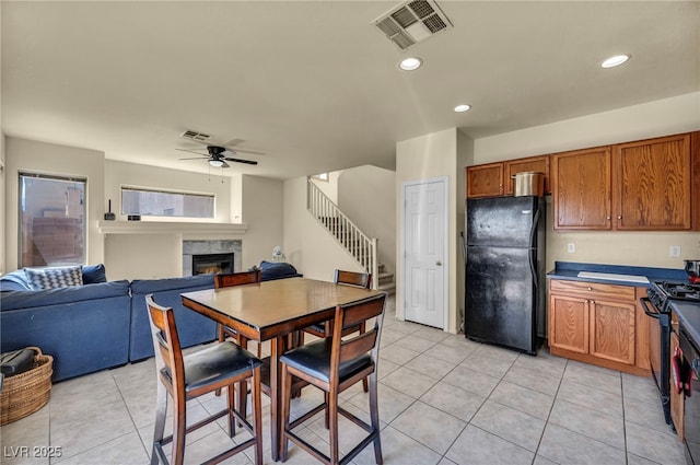 8421 Cheerful Brook Ave, Las Vegas, NV 89143 - dining area featuring a lit fireplace, ceiling fan, light tile patterned floors, stairway, and recessed lighting