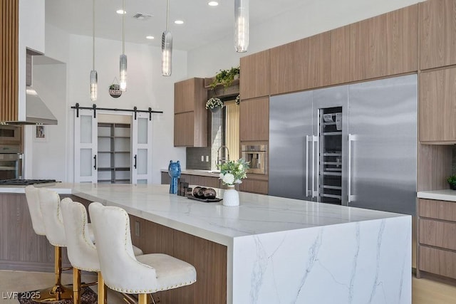 9233 Canyon Mesa Dr, Las Vegas, NV 89144 - kitchen with stainless steel appliances, modern cabinets, a barn door, light stone countertops, and decorative light fixtures