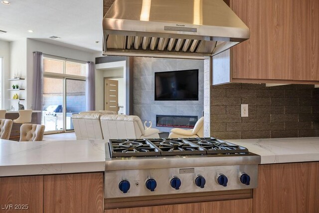 9233 Canyon Mesa Dr, Las Vegas, NV 89144 - kitchen with exhaust hood, stainless steel gas stovetop, open floor plan, a tile fireplace, and tasteful backsplash