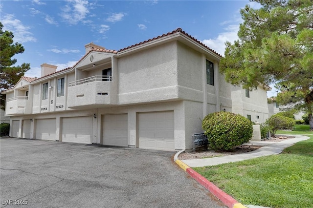 2633 S Durango Dr Unit 202, Las Vegas, NV 89117 - view of property exterior with stucco siding, a tiled roof, a garage, and a chimney