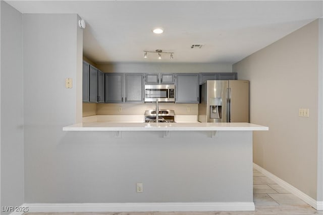 2633 S Durango Dr Unit 202, Las Vegas, NV 89117 - kitchen with appliances with stainless steel finishes, a peninsula, a kitchen breakfast bar, light countertops, and gray cabinets