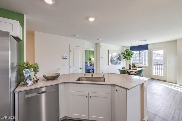 7955 Aurora Sky St Unit 631, North Las Vegas, NV 89084 - kitchen with appliances with stainless steel finishes, a peninsula, light stone counters, white cabinets, and light wood-type flooring