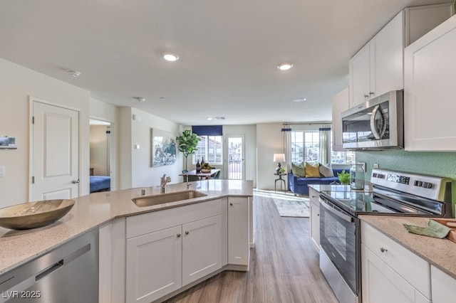 7955 Aurora Sky St Unit 631, North Las Vegas, NV 89084 - kitchen with appliances with stainless steel finishes, light wood-style floors, light stone counters, white cabinetry, and recessed lighting