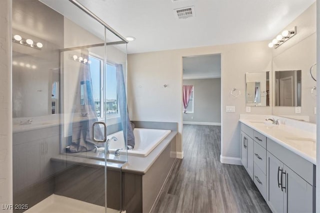 10058 Matter Overlook Dr, Las Vegas, NV 89178 - full bathroom featuring double vanity, plenty of natural light, a garden tub, and wood finished floors