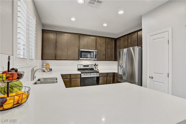 1113 Fragrant Cactus Ct, North Las Vegas, NV 89031 - kitchen featuring appliances with stainless steel finishes, light countertops, recessed lighting, dark brown cabinets, and a peninsula