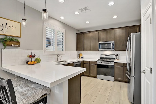 1113 Fragrant Cactus Ct, North Las Vegas, NV 89031 - kitchen with stainless steel appliances, a peninsula, dark brown cabinetry, backsplash, and light countertops