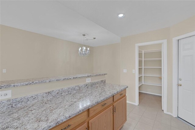 4713 Guma Way N, Las Vegas, NV 89031 - kitchen with light tile patterned floors, hanging light fixtures, a chandelier, recessed lighting, and light stone counters