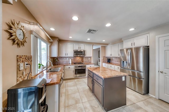 8914 Termoli St, Las Vegas, NV 89123 - kitchen featuring appliances with stainless steel finishes, light stone countertops, tasteful backsplash, a center island, and light tile patterned flooring
