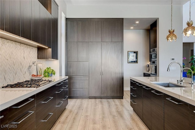 527 Serenity Point Dr, Henderson, NV 89012 - kitchen featuring backsplash, stainless steel gas cooktop, dark brown cabinets, light wood finished floors, and recessed lighting