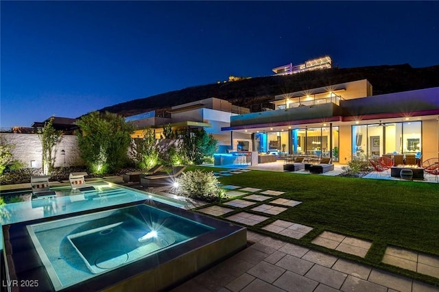 527 Serenity Point Dr, Henderson, NV 89012 - pool at night with an in-ground hot tub, a patio area, outdoor lounge area, and a yard