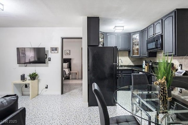 4955 Jeffreys St Unit 605, Las Vegas, NV 89119 - kitchen with black appliances, dark countertops, dark speckled floor, and glass insert cabinets