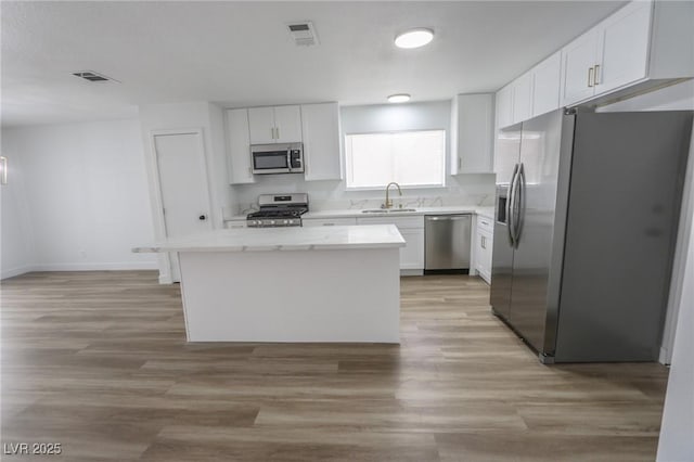 4269 Roanridge Ave, Las Vegas, NV 89120 - kitchen with stainless steel appliances, a kitchen island, white cabinetry, and light wood-type flooring