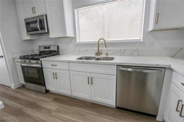 4269 Roanridge Ave, Las Vegas, NV 89120 - kitchen featuring appliances with stainless steel finishes, white cabinetry, light wood finished floors, and light stone countertops