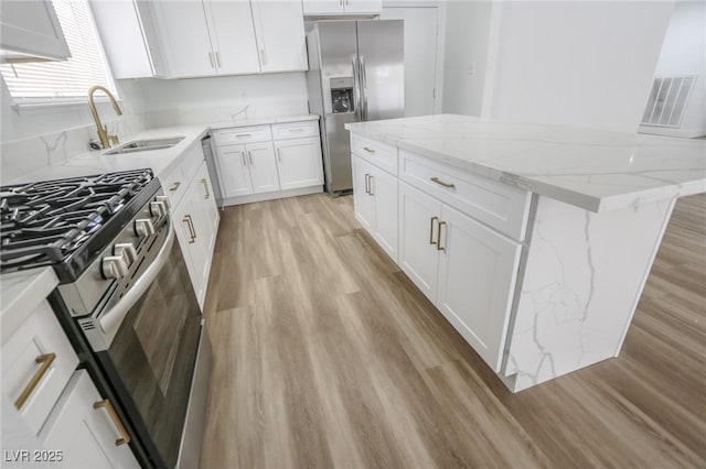 4269 Roanridge Ave, Las Vegas, NV 89120 - kitchen featuring stainless steel appliances, light wood finished floors, a kitchen island, and white cabinetry