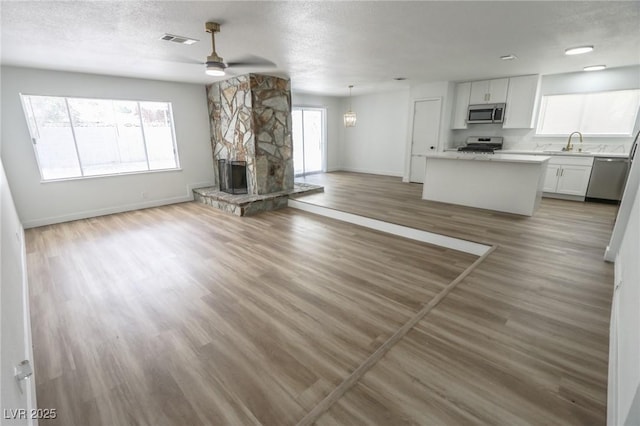 4269 Roanridge Ave, Las Vegas, NV 89120 - unfurnished living room with ceiling fan, healthy amount of natural light, a stone fireplace, and a textured ceiling