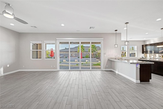 274 Chartan Ave, Las Vegas, NV 89183 - kitchen featuring light wood-style floors, open floor plan, a ceiling fan, light stone countertops, and dark brown cabinetry