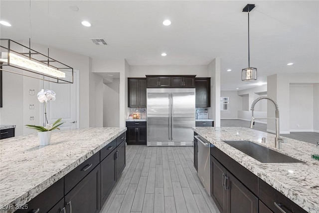274 Chartan Ave, Las Vegas, NV 89183 - kitchen featuring appliances with stainless steel finishes, light stone countertops, recessed lighting, light wood finished floors, and decorative light fixtures