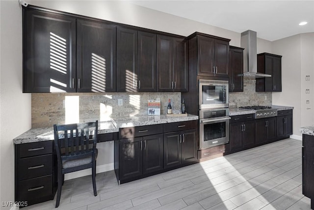 274 Chartan Ave, Las Vegas, NV 89183 - kitchen featuring stainless steel appliances, wall chimney exhaust hood, wood finish floors, backsplash, and light stone counters