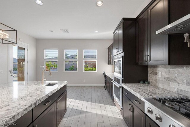 274 Chartan Ave, Las Vegas, NV 89183 - kitchen featuring appliances with stainless steel finishes, decorative backsplash, ventilation hood, recessed lighting, and light stone counters