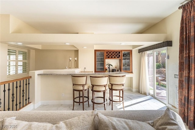 11005 Inverlochy Ct, Las Vegas, NV 89141 - kitchen featuring light marble finish floors, glass insert cabinets, a breakfast bar, recessed lighting, and healthy amount of natural light