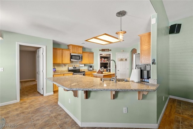 231 Bristle Cone, Pahrump, NV 89048 - kitchen featuring appliances with stainless steel finishes, a peninsula, a kitchen breakfast bar, and light stone counters