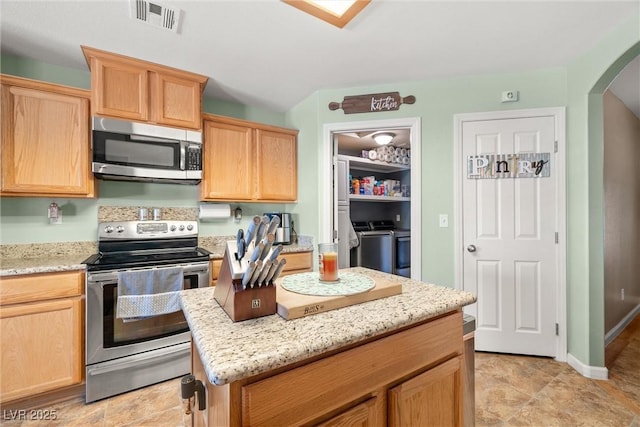 231 Bristle Cone, Pahrump, NV 89048 - kitchen with stainless steel appliances, washing machine and clothes dryer, arched walkways, and light brown cabinets