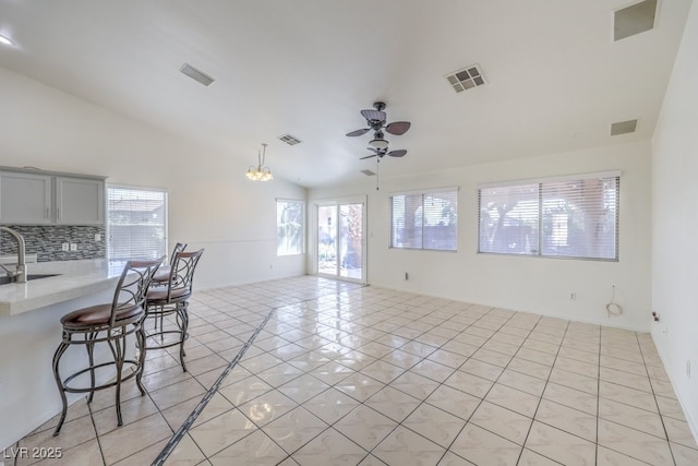 4010 Hemphill St, North Las Vegas, NV 89032 - kitchen with lofted ceiling, light countertops, a kitchen breakfast bar, a ceiling fan, and light tile patterned flooring