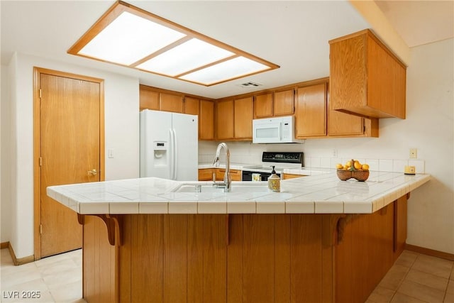 2040 Tucuman Ave, Pahrump, NV 89048 - kitchen featuring white appliances, a peninsula, brown cabinetry, light tile patterned floors, and a kitchen breakfast bar