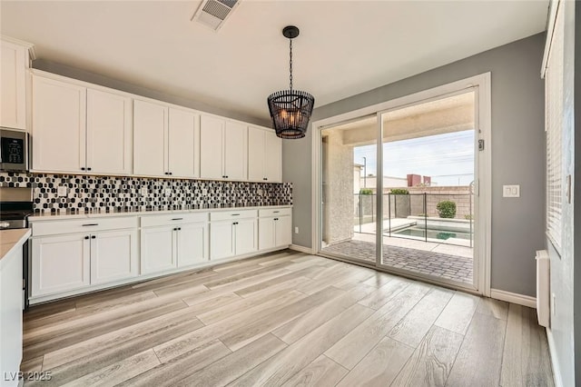 5990 Viscaya Grove St, Las Vegas, NV 89118 - kitchen with stainless steel appliances, light wood finished floors, white cabinetry, and backsplash