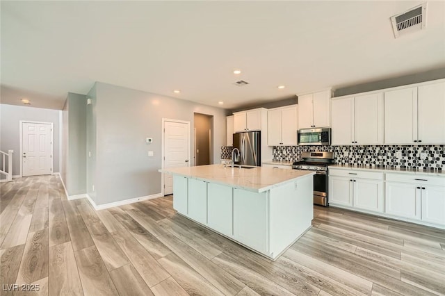 5990 Viscaya Grove St, Las Vegas, NV 89118 - kitchen with appliances with stainless steel finishes, a kitchen island with sink, white cabinets, decorative backsplash, and light countertops