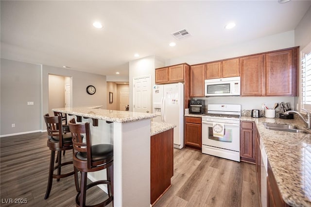 7252 Blowing Breeze Ave, Las Vegas, NV 89179 - kitchen featuring white appliances, wood finished floors, a breakfast bar area, a kitchen island, and recessed lighting