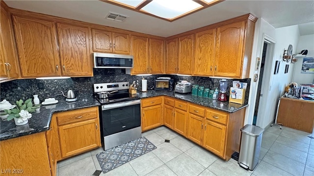 4910 Marywood Ct, Pahrump, NV 89061 - kitchen with appliances with stainless steel finishes, decorative backsplash, dark stone counters, and brown cabinets