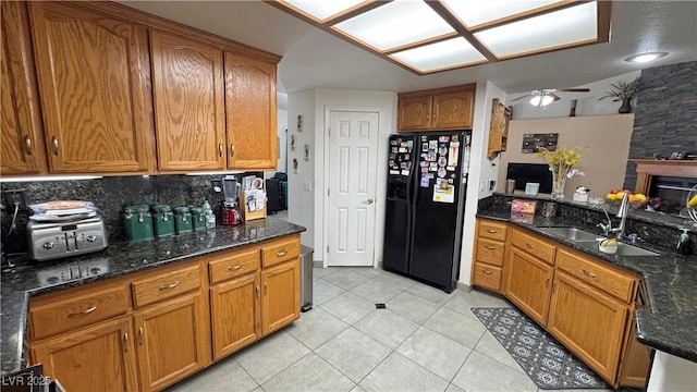 4910 Marywood Ct, Pahrump, NV 89061 - kitchen featuring black fridge with ice dispenser, ceiling fan, light tile patterned flooring, brown cabinetry, and dark stone counters
