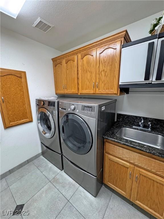 4910 Marywood Ct, Pahrump, NV 89061 - washroom featuring cabinet space, separate washer and dryer, light tile patterned floors, and a textured ceiling