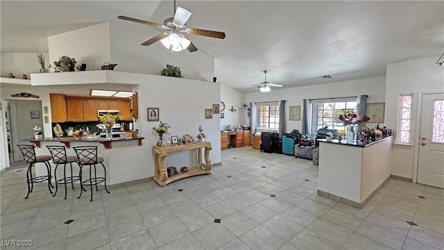 4910 Marywood Ct, Pahrump, NV 89061 - kitchen with a ceiling fan, brown cabinetry, dark countertops, a breakfast bar, and a peninsula