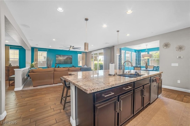 2154 Tortona St, Henderson, NV 89044 - kitchen featuring light wood-type flooring, dishwasher, light stone countertops, decorative light fixtures, and a breakfast bar area
