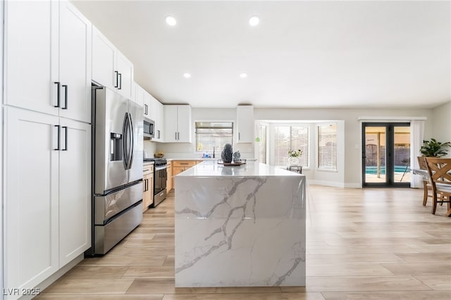5570 Palm St, Las Vegas, NV 89120 - kitchen with stainless steel appliances, a center island, light wood-type flooring, recessed lighting, and light stone countertops