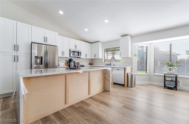 5570 Palm St, Las Vegas, NV 89120 - kitchen featuring stainless steel appliances, a kitchen island, light countertops, lofted ceiling, and white cabinets