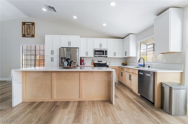 5570 Palm St, Las Vegas, NV 89120 - kitchen featuring stainless steel appliances, lofted ceiling, a kitchen island, light wood-type flooring, and light countertops