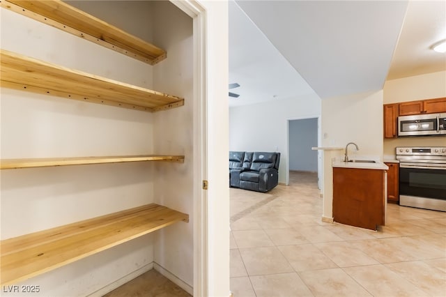 2141 Hussium Hills St Unit 108, Las Vegas, NV 89108 - kitchen featuring stainless steel appliances, open shelves, light countertops, brown cabinetry, and open floor plan