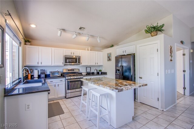 1844 Ghost Trace Ave, Las Vegas, NV 89183 - kitchen with appliances with stainless steel finishes, light tile patterned floors, a center island, a kitchen breakfast bar, and lofted ceiling