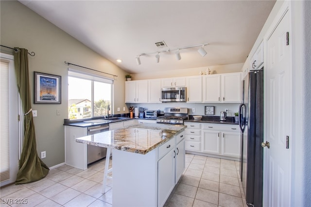 1844 Ghost Trace Ave, Las Vegas, NV 89183 - kitchen featuring stainless steel appliances, a center island, white cabinetry, light tile patterned floors, and vaulted ceiling