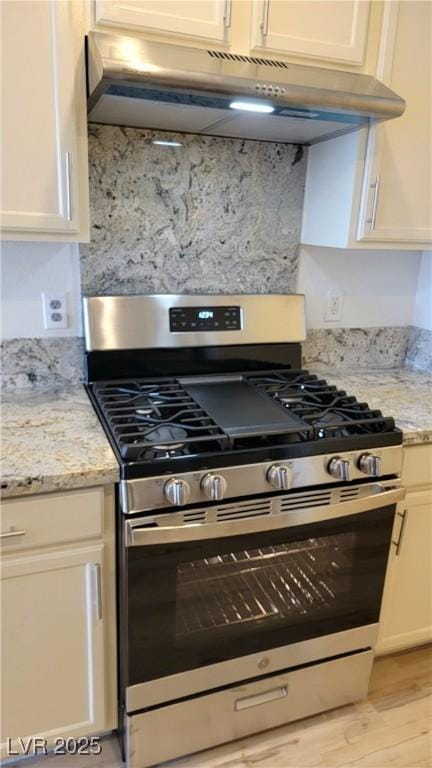 3930 Starfield Ln, Las Vegas, NV 89147 - kitchen with stainless steel range with gas stovetop, under cabinet range hood, light wood finished floors, and light stone countertops
