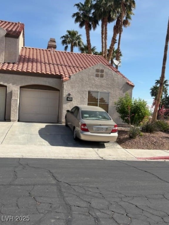 1701 Comstock Dr, Henderson, NV 89014 - mediterranean / spanish home with driveway, a chimney, a tiled roof, an attached garage, and stucco siding