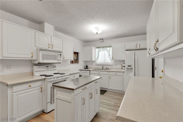 909 Biljac St, Las Vegas, NV 89145 - kitchen featuring white appliances, a textured ceiling, white cabinetry, and light wood finished floors