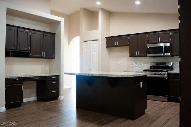 904 Swift Bear St, Henderson, NV 89002 - kitchen with stainless steel appliances, tasteful backsplash, arched walkways, dark wood-style flooring, and high vaulted ceiling