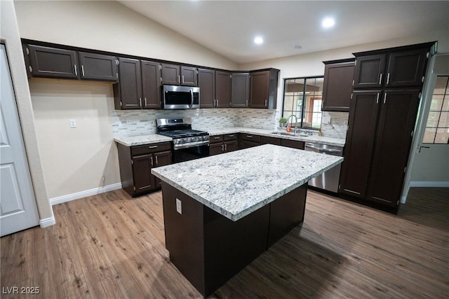 904 Swift Bear St, Henderson, NV 89002 - kitchen with appliances with stainless steel finishes, tasteful backsplash, vaulted ceiling, a center island, and wood finished floors