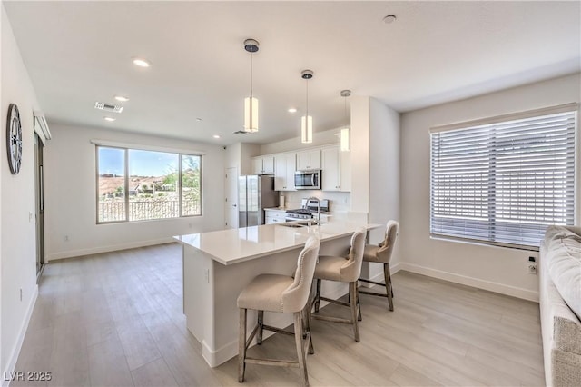 187 Palm Fox Ct, Henderson, NV 89011 - kitchen with appliances with stainless steel finishes, white cabinets, light wood-style flooring, open floor plan, and light countertops