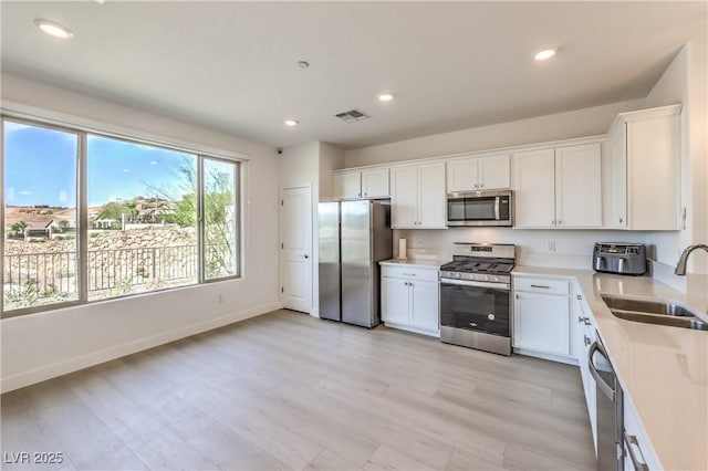 187 Palm Fox Ct, Henderson, NV 89011 - kitchen featuring appliances with stainless steel finishes, white cabinets, light countertops, recessed lighting, and light wood-type flooring